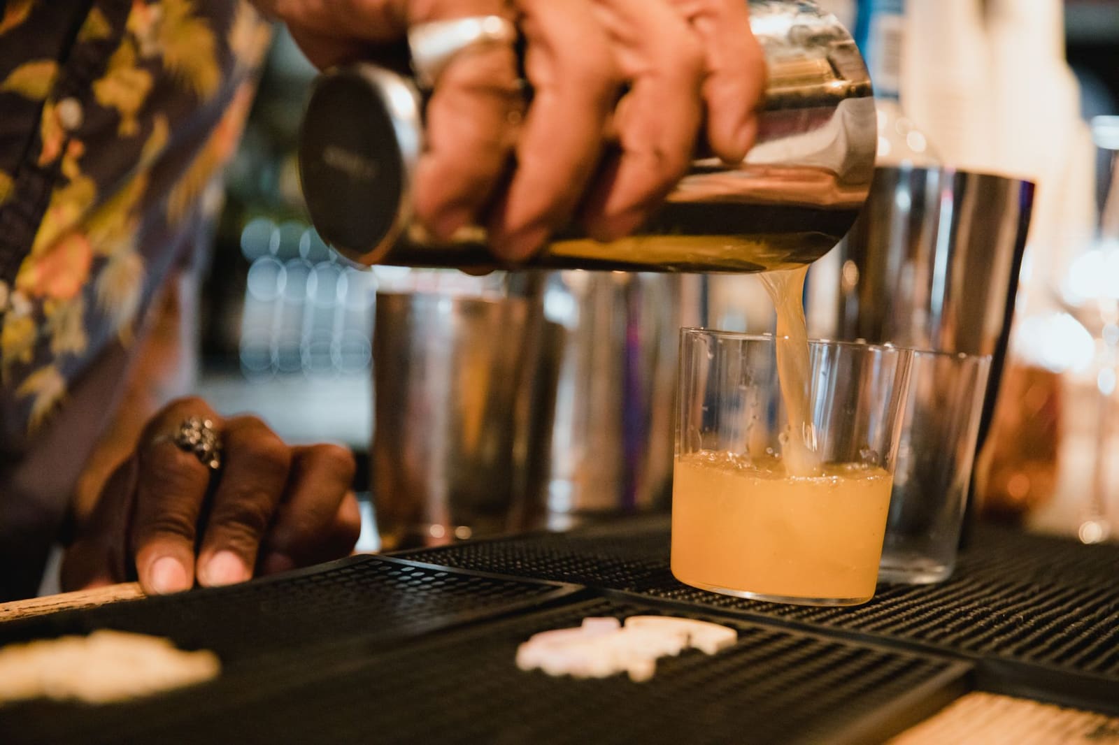 Bartender schenkt maple syrup in een cocktailglas tijdens het maken van een herfstdrank