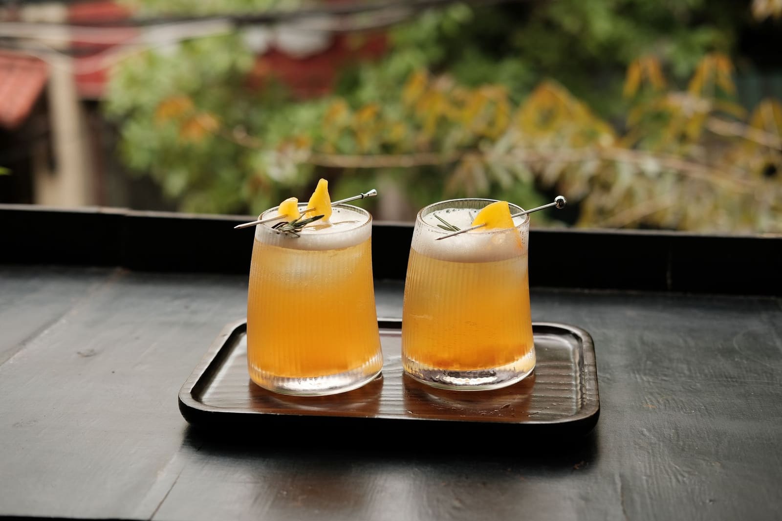 Een amberkleurige whiskeycocktail met groot ijsblok op een donkere bar in herfstsfeer