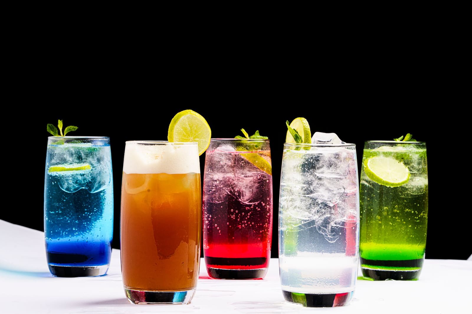 Rij gekleurde cocktails met garnering op een bar