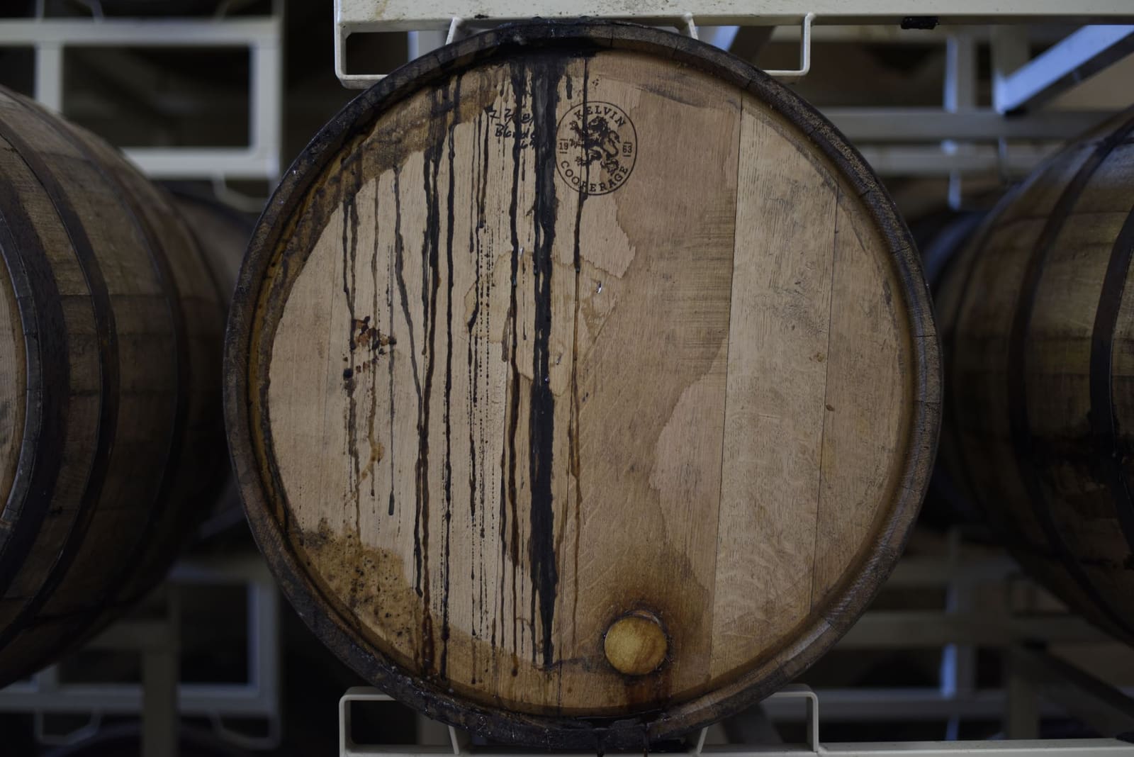 Rijen eikenhouten whiskyvaten in een distilleerderij, symbool voor de discussie over Scotch en Engelse single malt