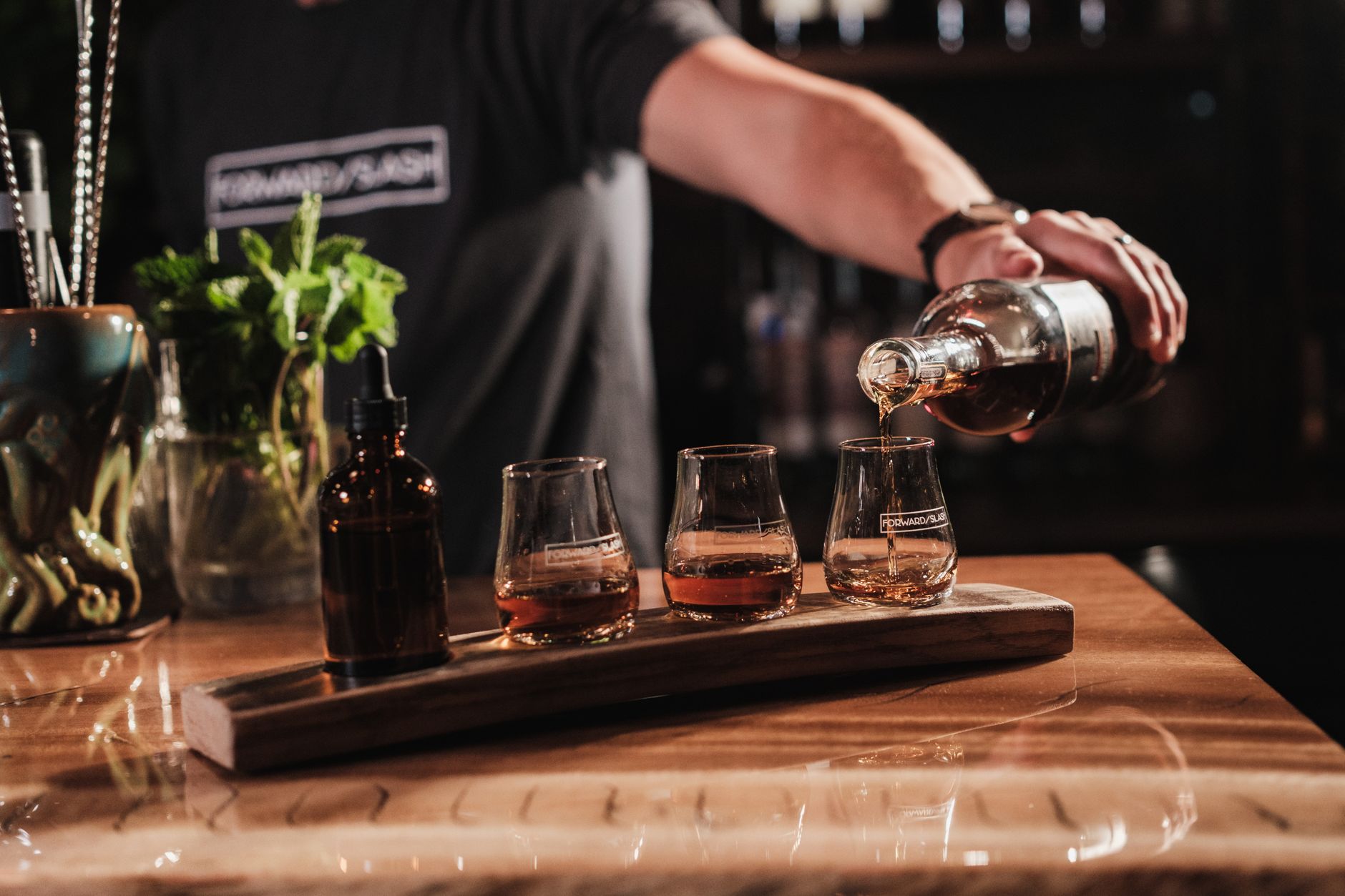 Fles Ierse whiskeylikeur op een barblad tussen glazen en ijs
