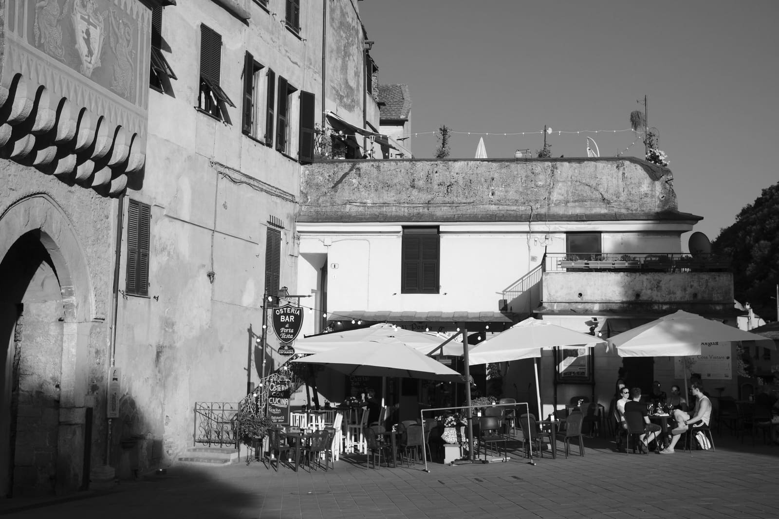 Terras van een Italiaans café met kleine ronde tafeltjes en parasols.