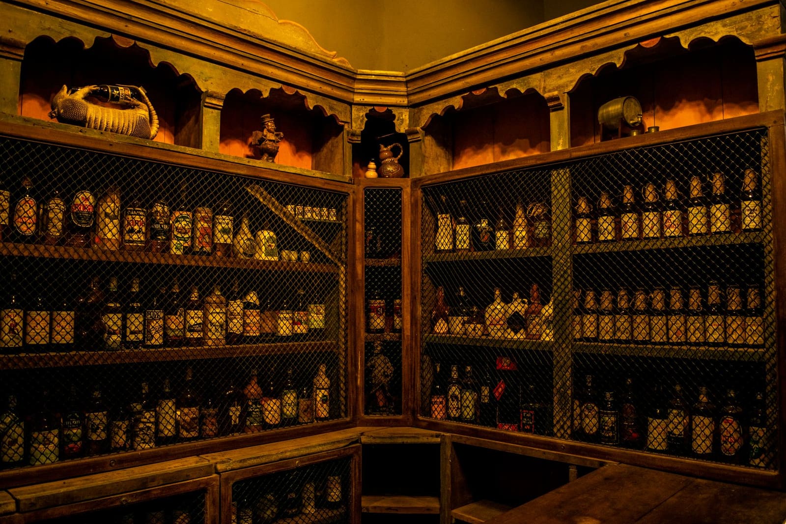 Plank vol drankflessen achter een bar in een cocktailbar