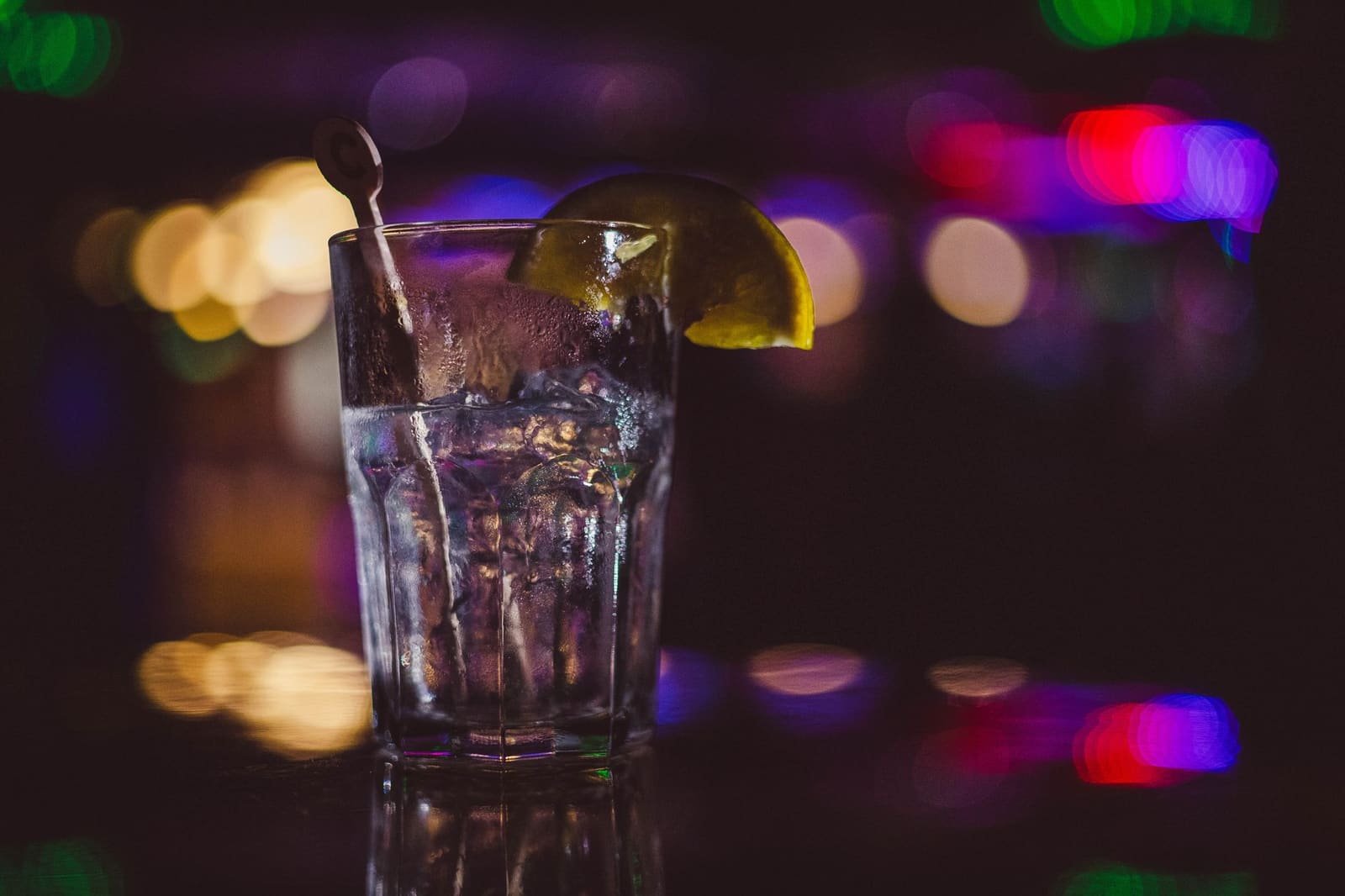 Een enkel cocktailglas met ijs staat klaar op een gepolijste bar