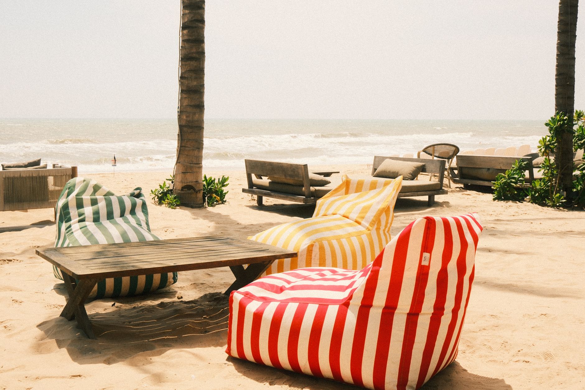Bezoekers genieten van cocktails op een zonnig strandterras tijdens een beachclub-evenement