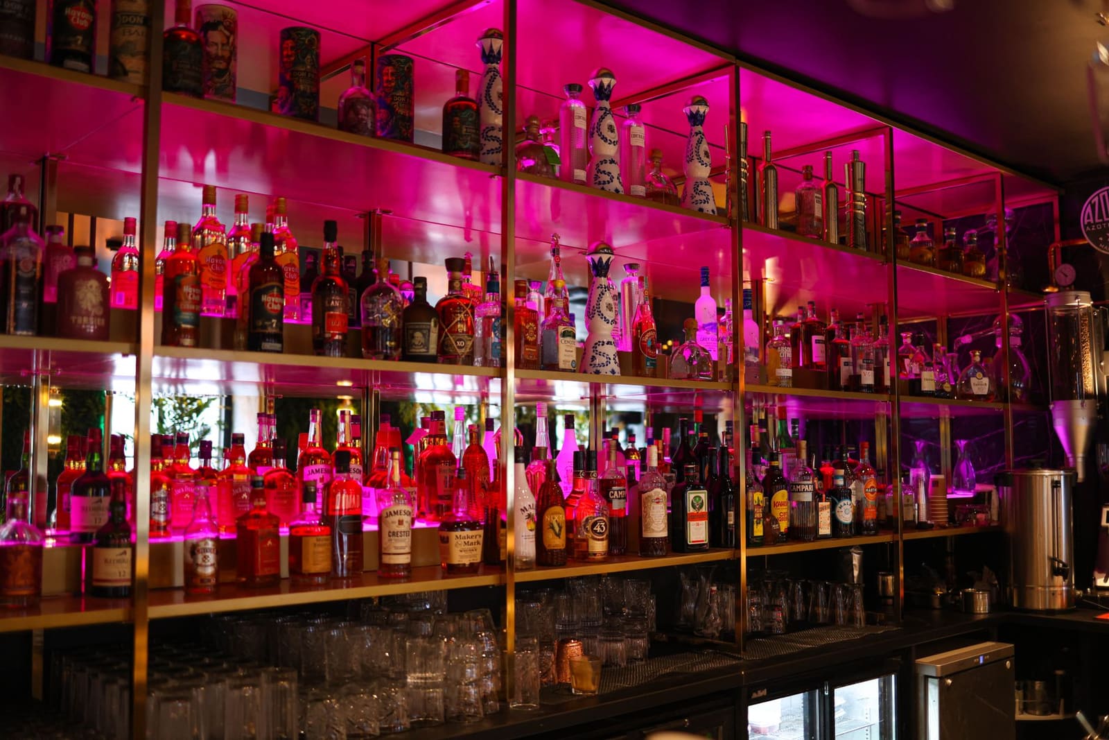 Flessen tequila en mezcal netjes uitgestald op een plank achter de bar
