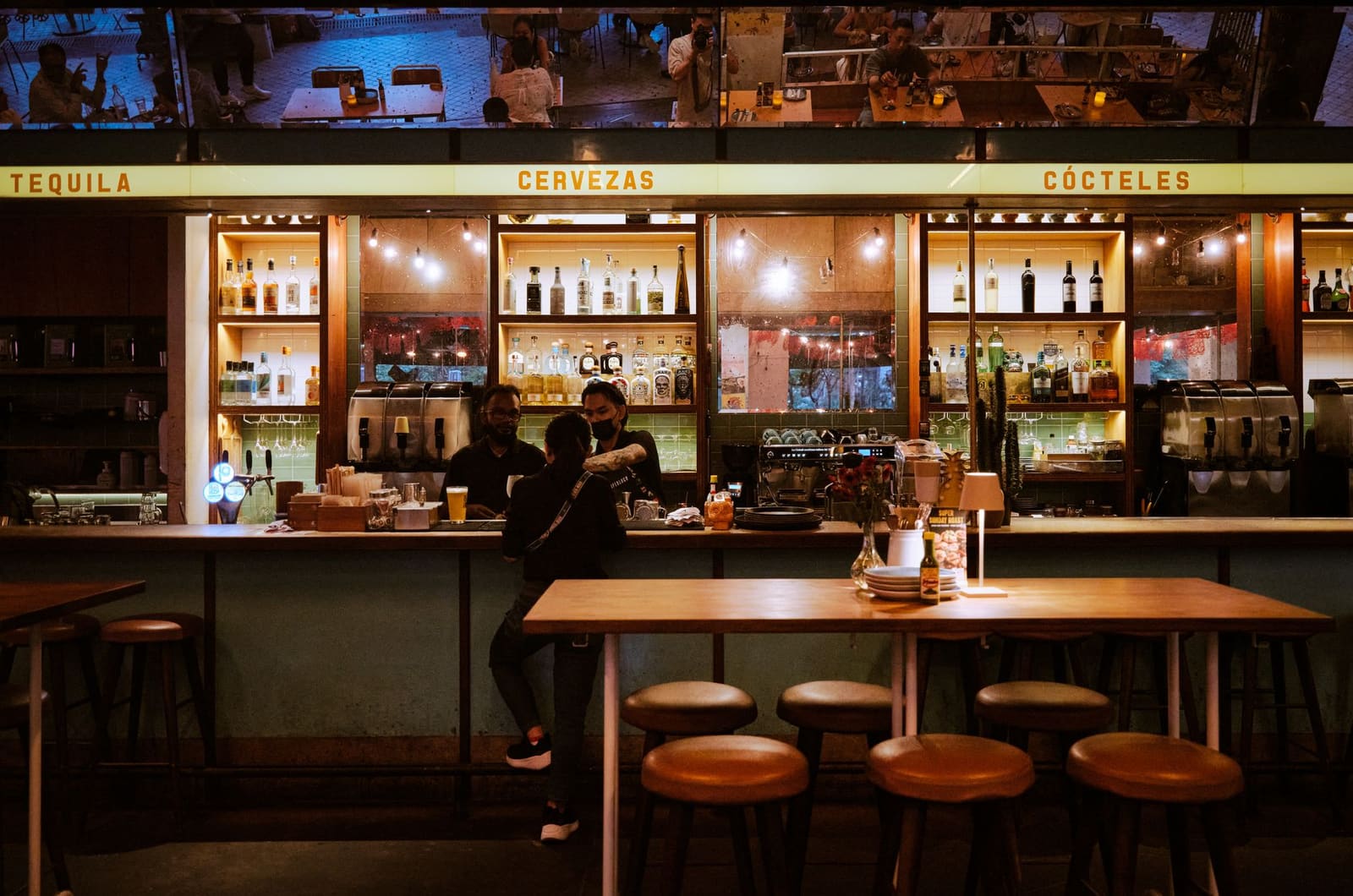 Bartender serveert een gekleurde tequila cocktail aan de bar van een moderne tequilabar