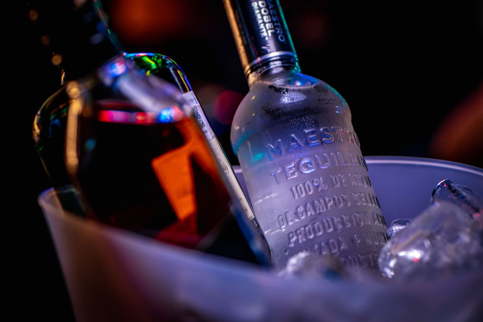Close-up van een fles premium tequila met een glas ernaast op de bar