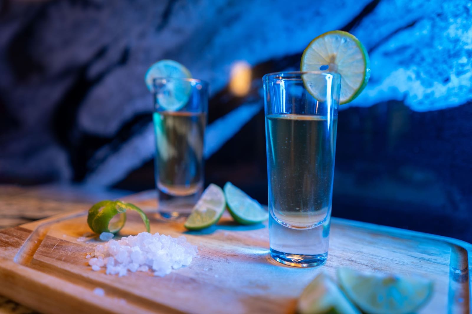 Grote fles blanco tequila van 3,75 liter op een barplank tussen glazen