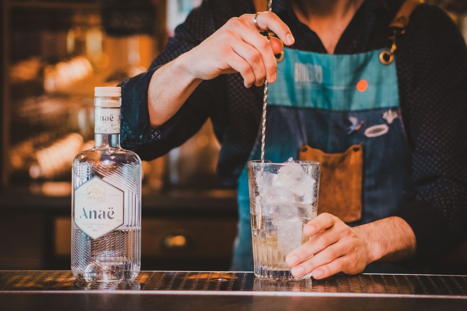 Gin wordt geschonken uit een fles boven een glas met ijs