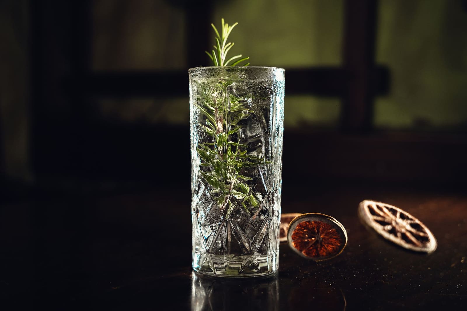 Glas longdrink met gin, tonic en ijs op een lichte ondergrond