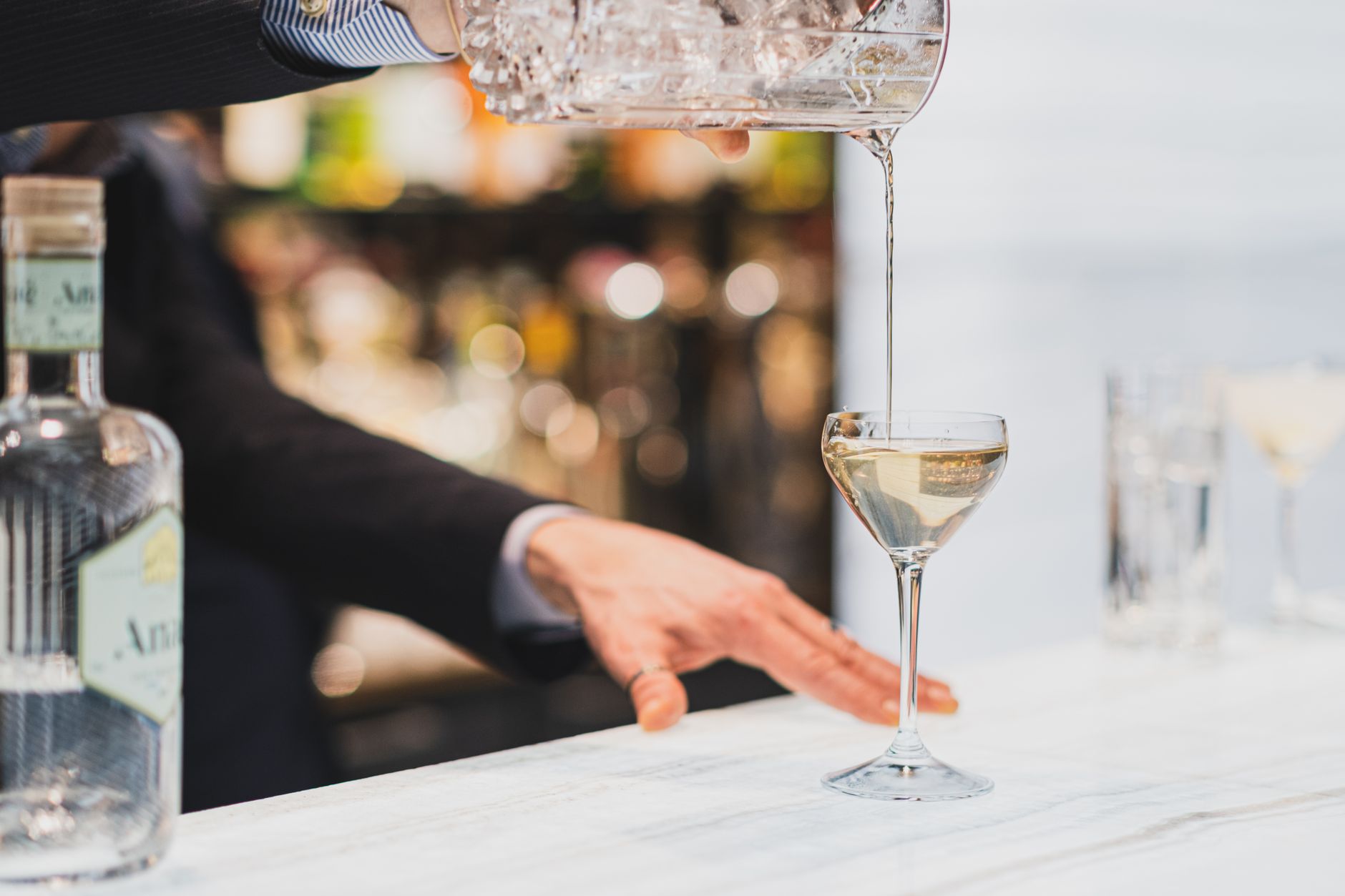 Bartender schenkt een gin Martini in een glas achter de bar, klaar om te serveren