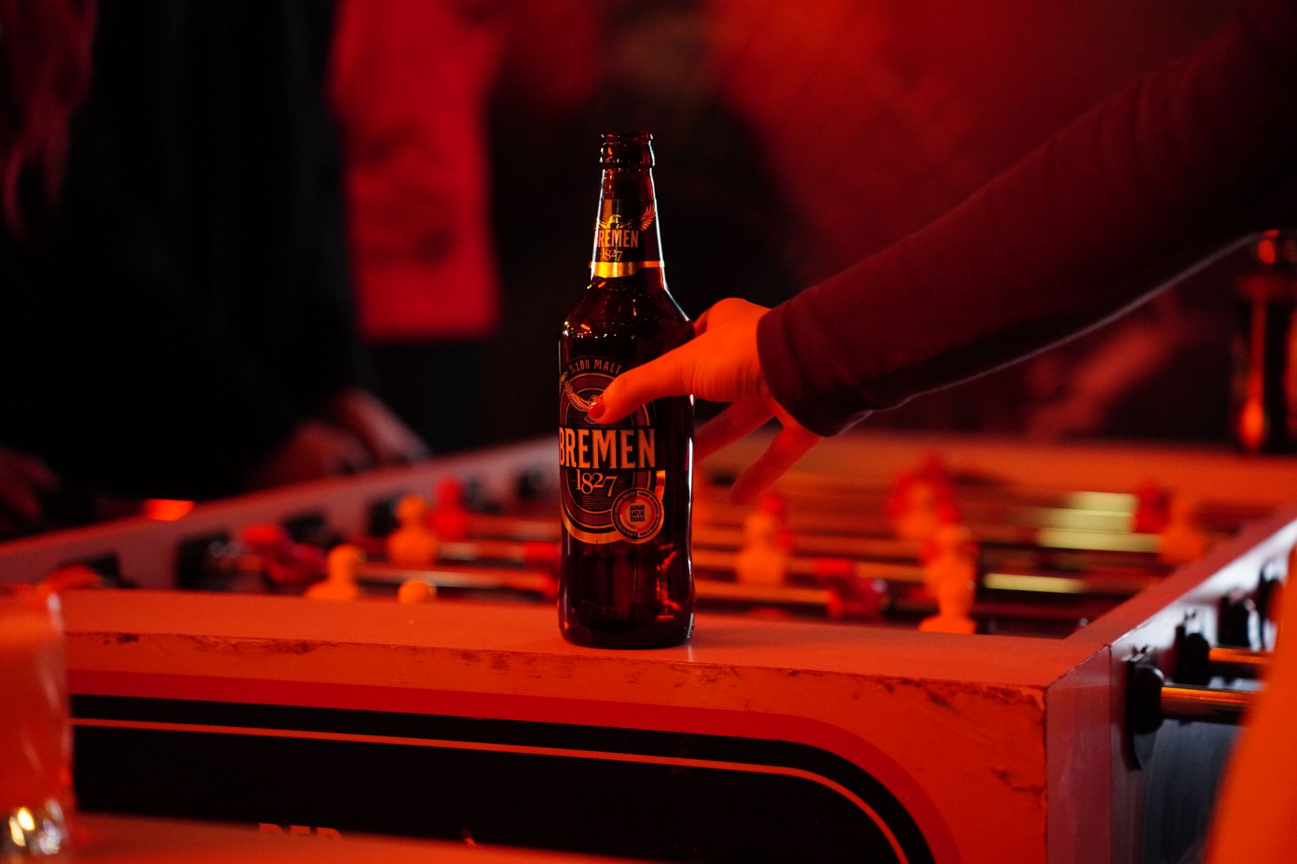 Iemand houdt een koud biertje vast aan de bar, symbool voor het guilty pleasure bier van brouwers