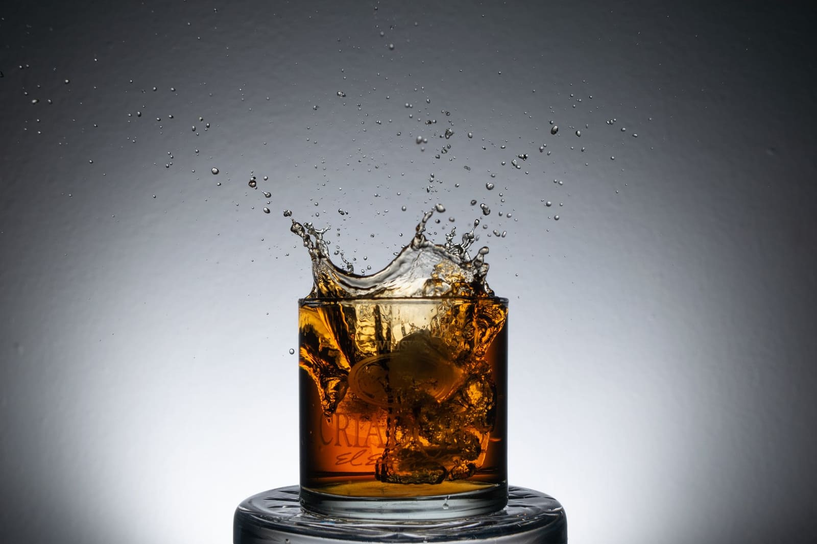Een glas whiskey met grote ijsblokken, klaar om geserveerd te worden in een gezellige bar
