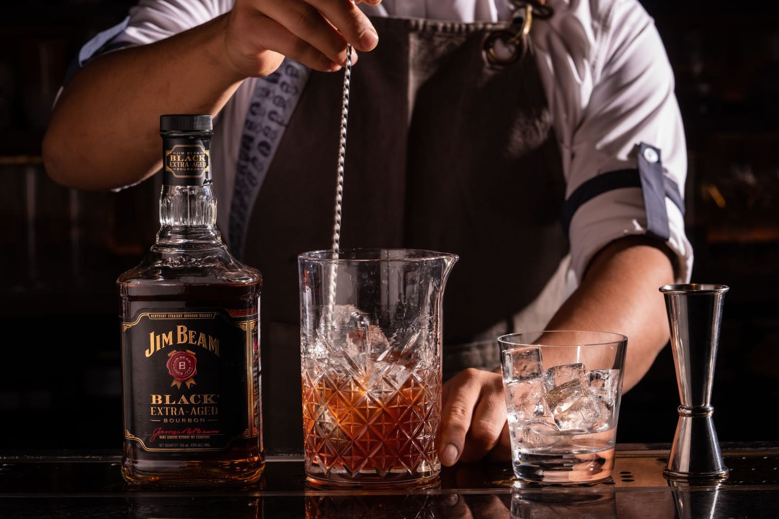 Een bartender roert een Negroni-variatie achter de bar met ijs