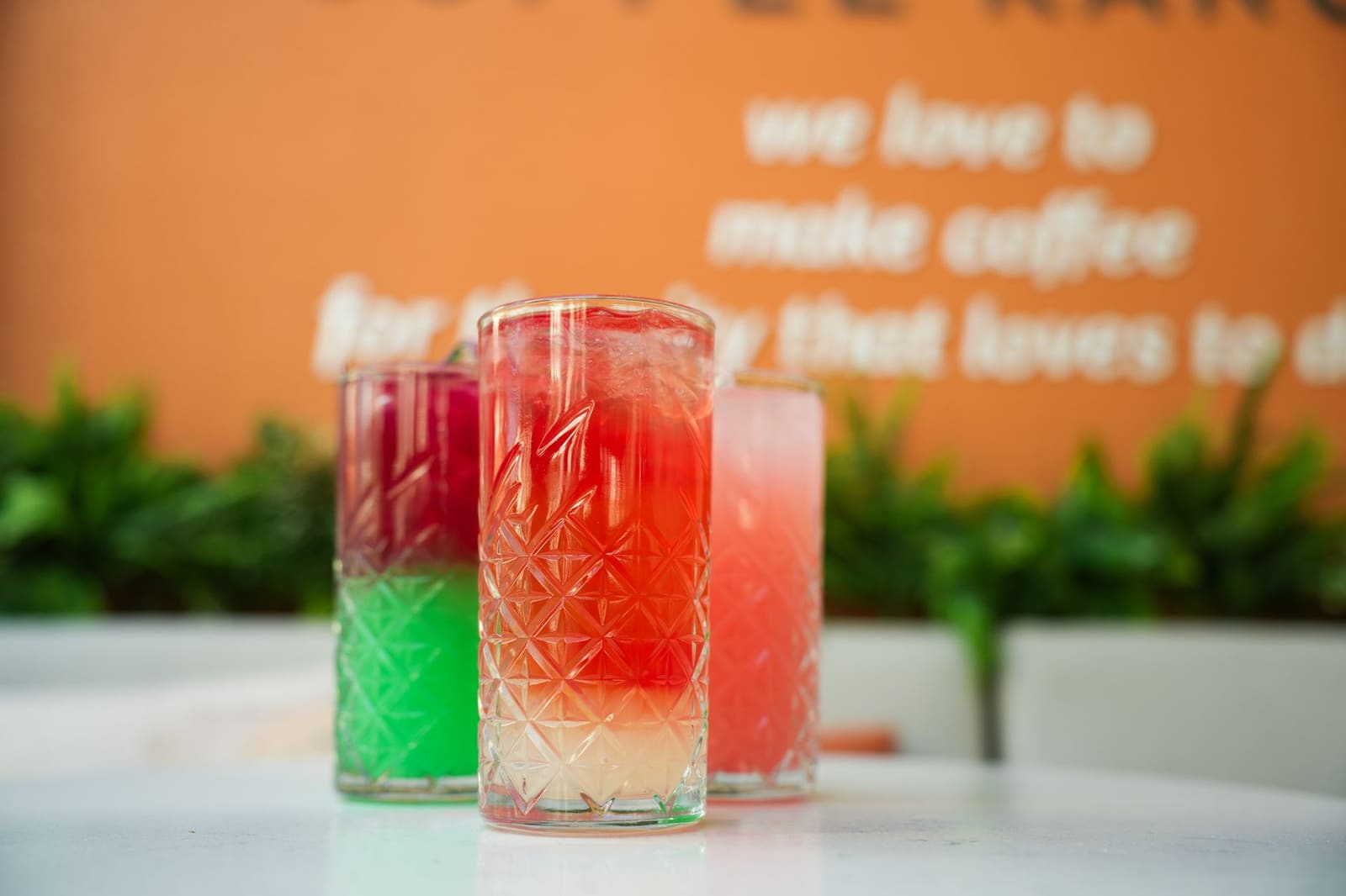 Rij gekleurde cocktails met garnering op een bar