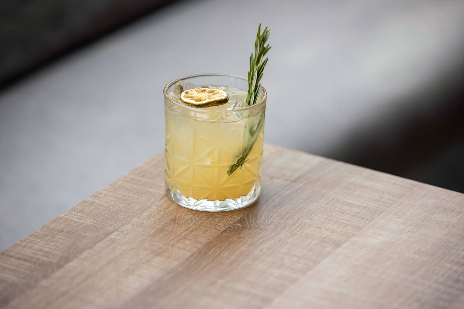 Cocktail met verzorgde citrusgarnering geserveerd op een houten bar
