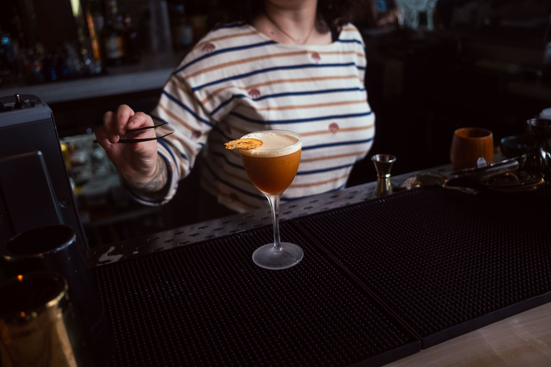 Bartender werkt achter de bar aan een cocktail met vodka en verse garnering in Italiaanse setting