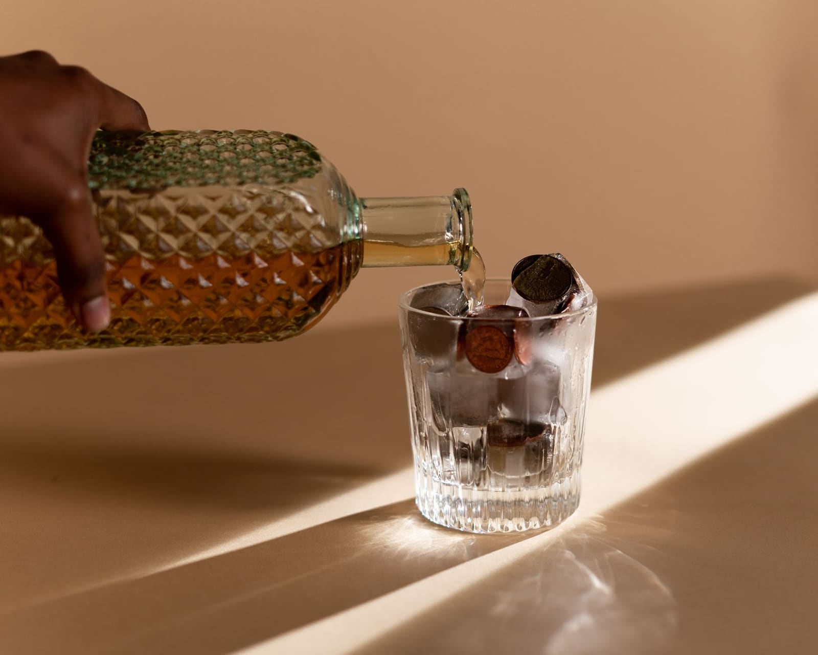 Amber whisky wordt ingeschonken in een glas met ijs