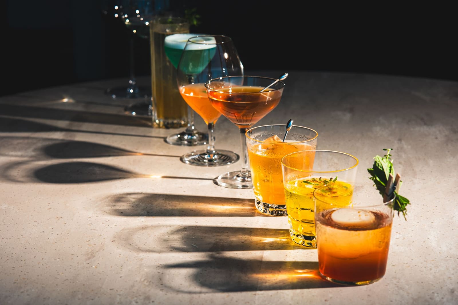 Rij gekleurde cocktails met garnering op een bar