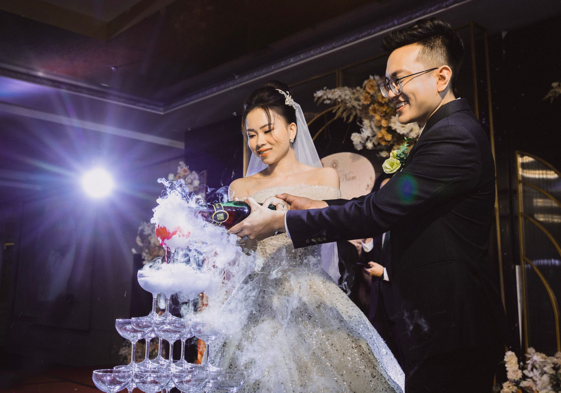Een getrapte champagnetoren van glazen waarin bubbels naar beneden stromen tijdens een feest