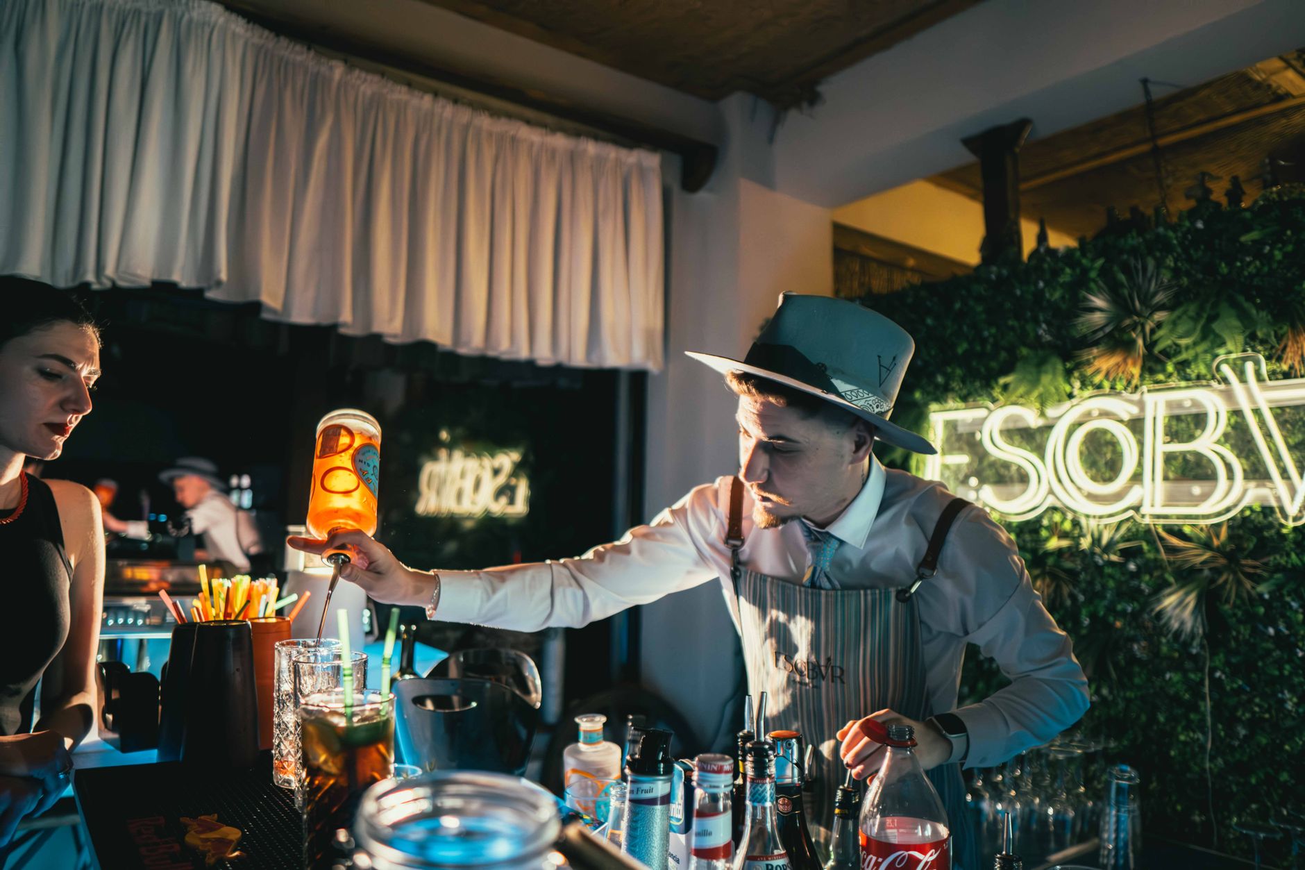Filmcrew aan het werk in een cocktailbar terwijl een bartender achter de toog drankjes serveert