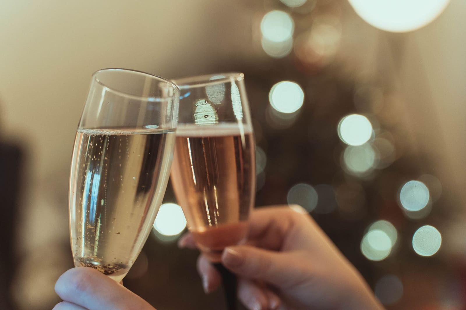 Glas prosecco met fijne bubbels naast een open fles op een lichte achtergrond.