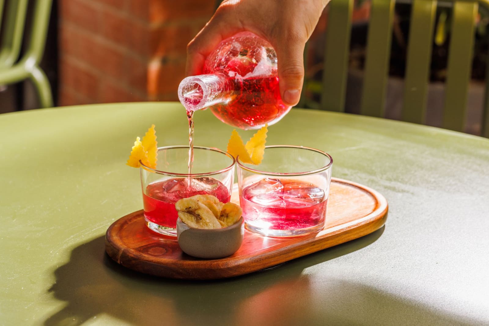Negroni in een tumbler met een grote ijsblok en een gedraaide sinaasappelschil.