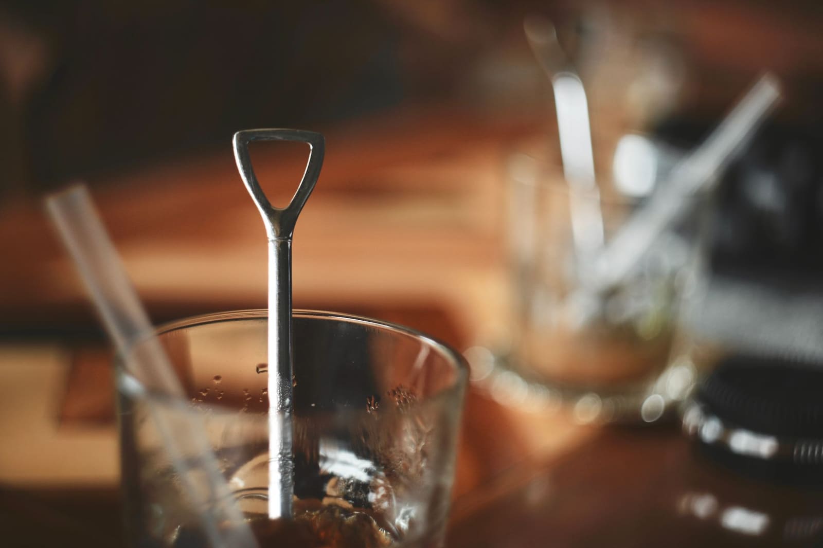 Een bartender roert een cocktail rond in een mixglas met een lange barlepel en ijsblokjes.