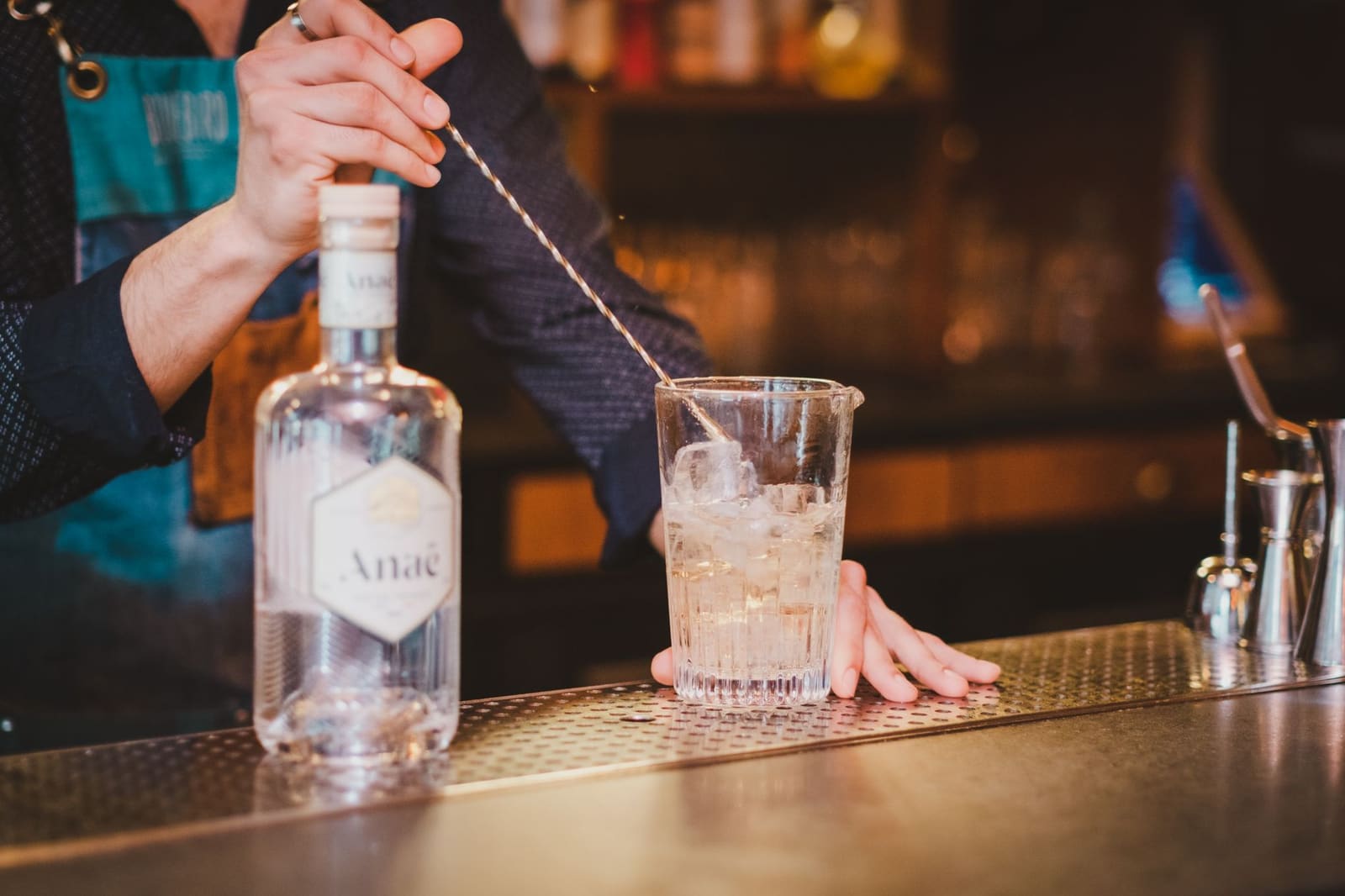 Bartender roert een cocktail in een mengglas met een barlepel