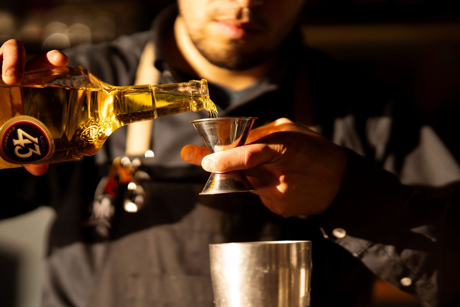 Bartender schenkt sterkedrank uit een fles achter de bar