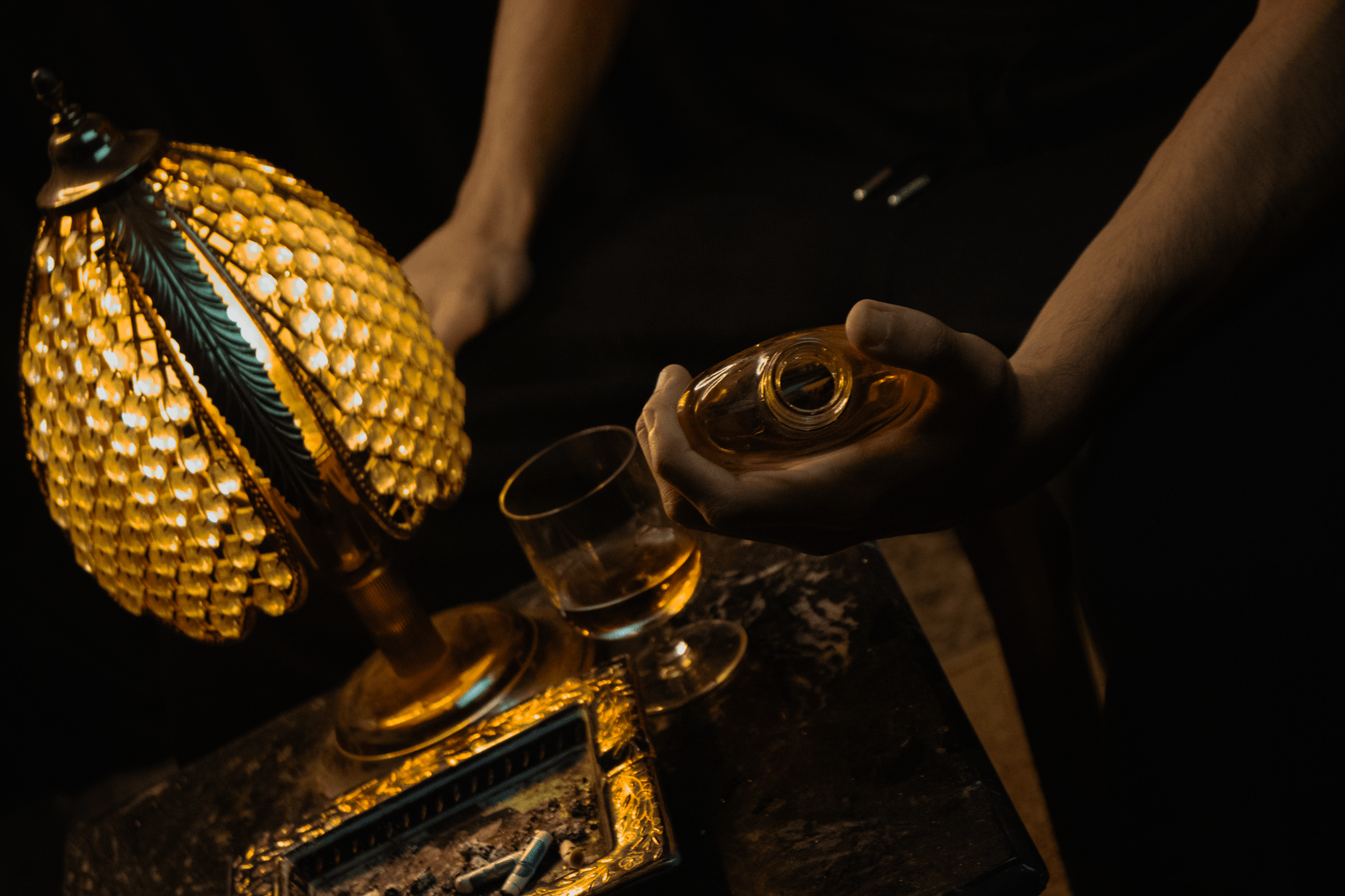 Een glas amberkleurige bourbon op een donkere houten bar, met de kleur van de whiskey goed zichtbaar
