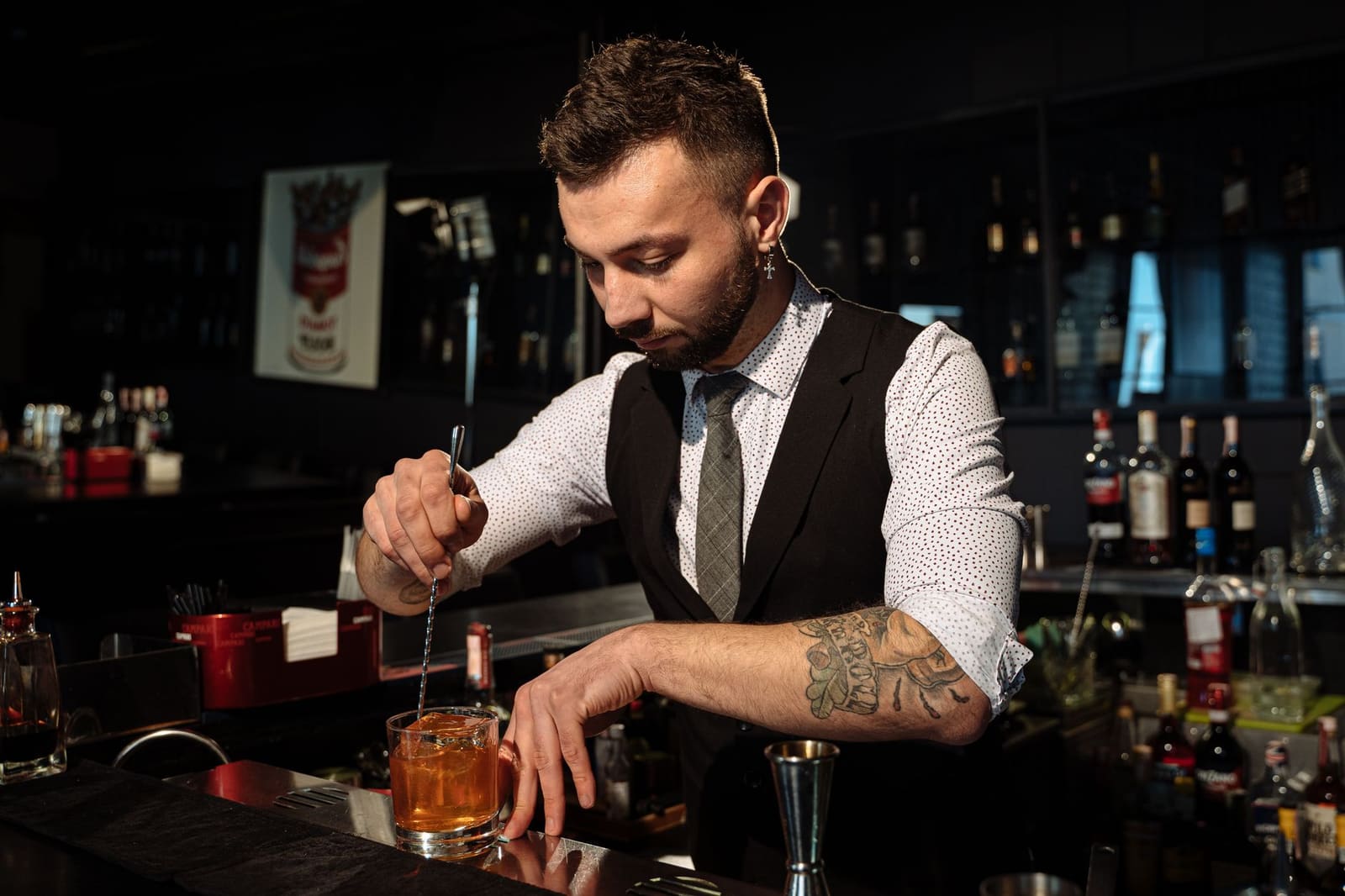 Bartender roert een cocktail met ijs in een mengglas