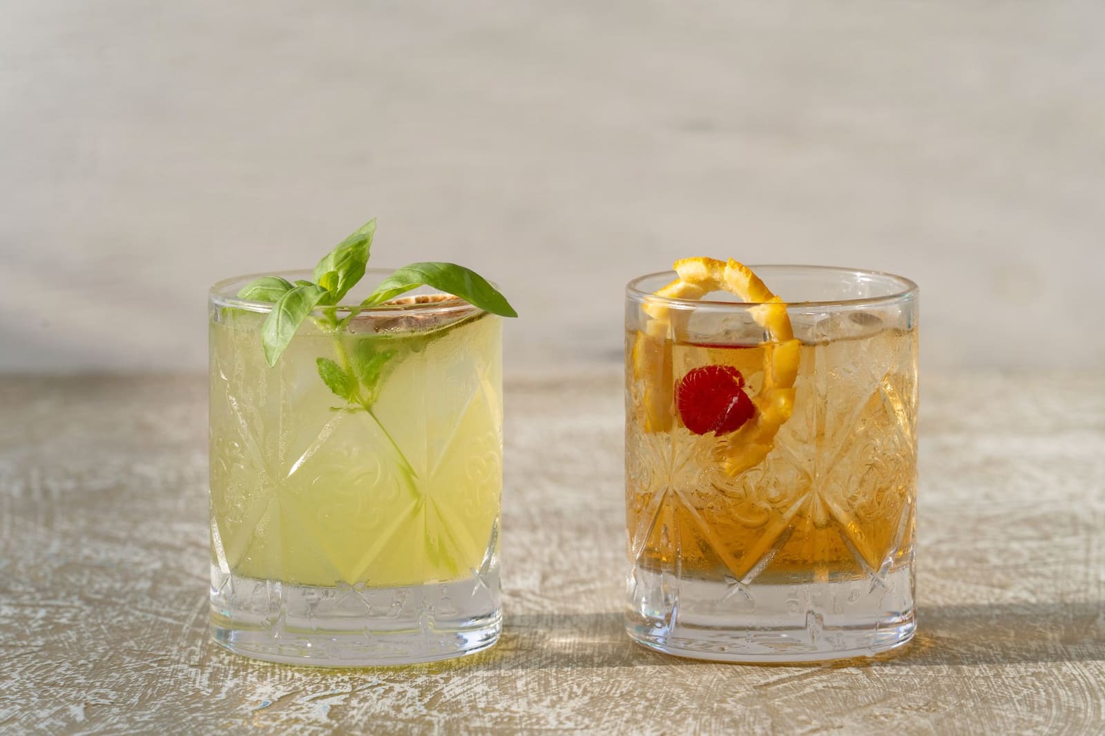 Een lichtgekleurde witte Negroni cocktail geserveerd op ijs met een citrusschil als garnering