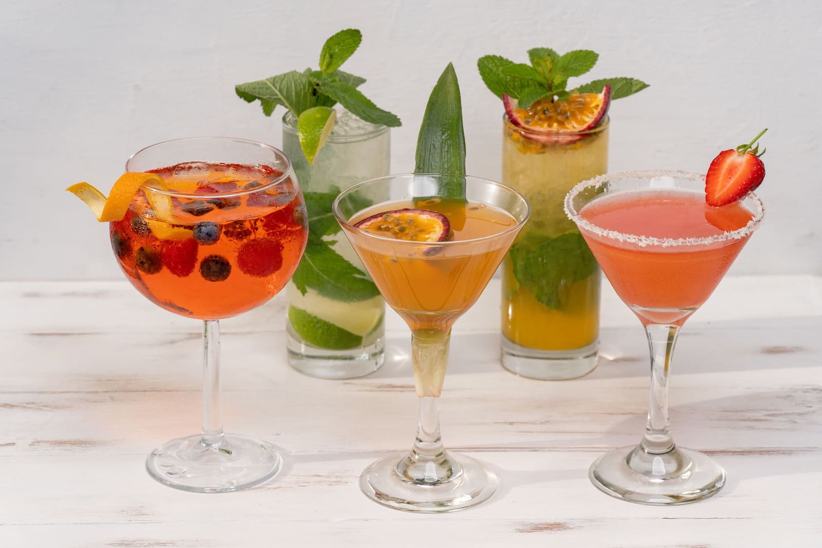 Rij gekleurde cocktails met garnering op een bar
