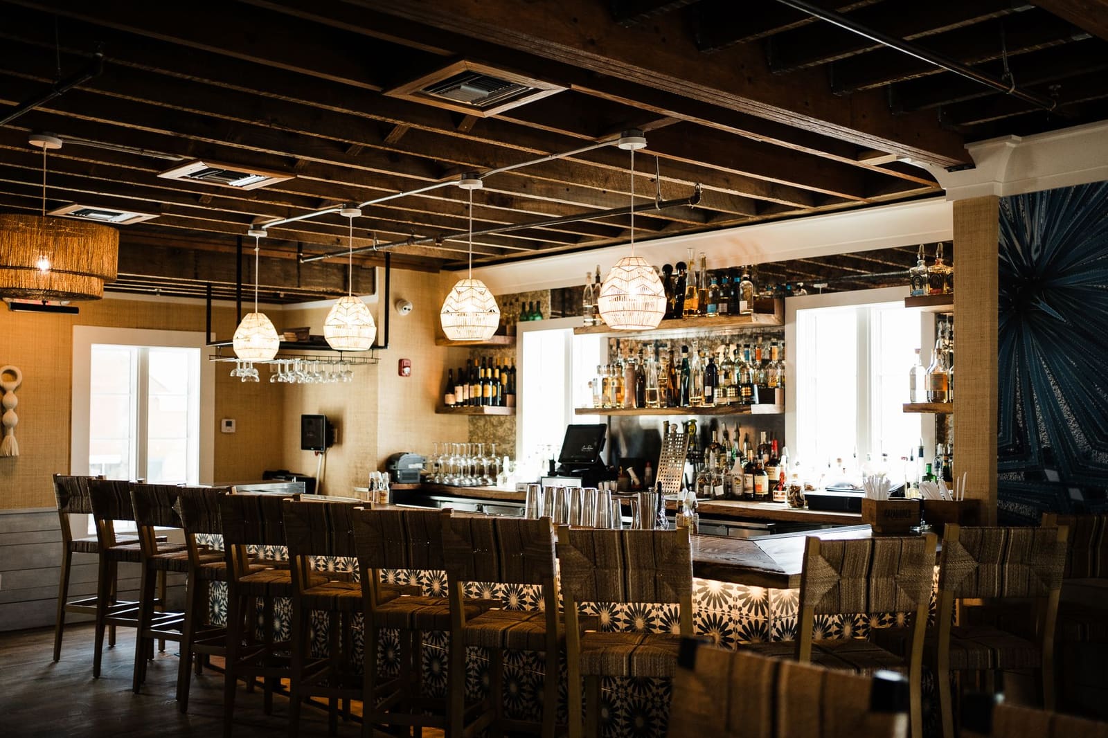 Lege bar met kruk­ken en flessen op verlichte schappen achter houten toog.