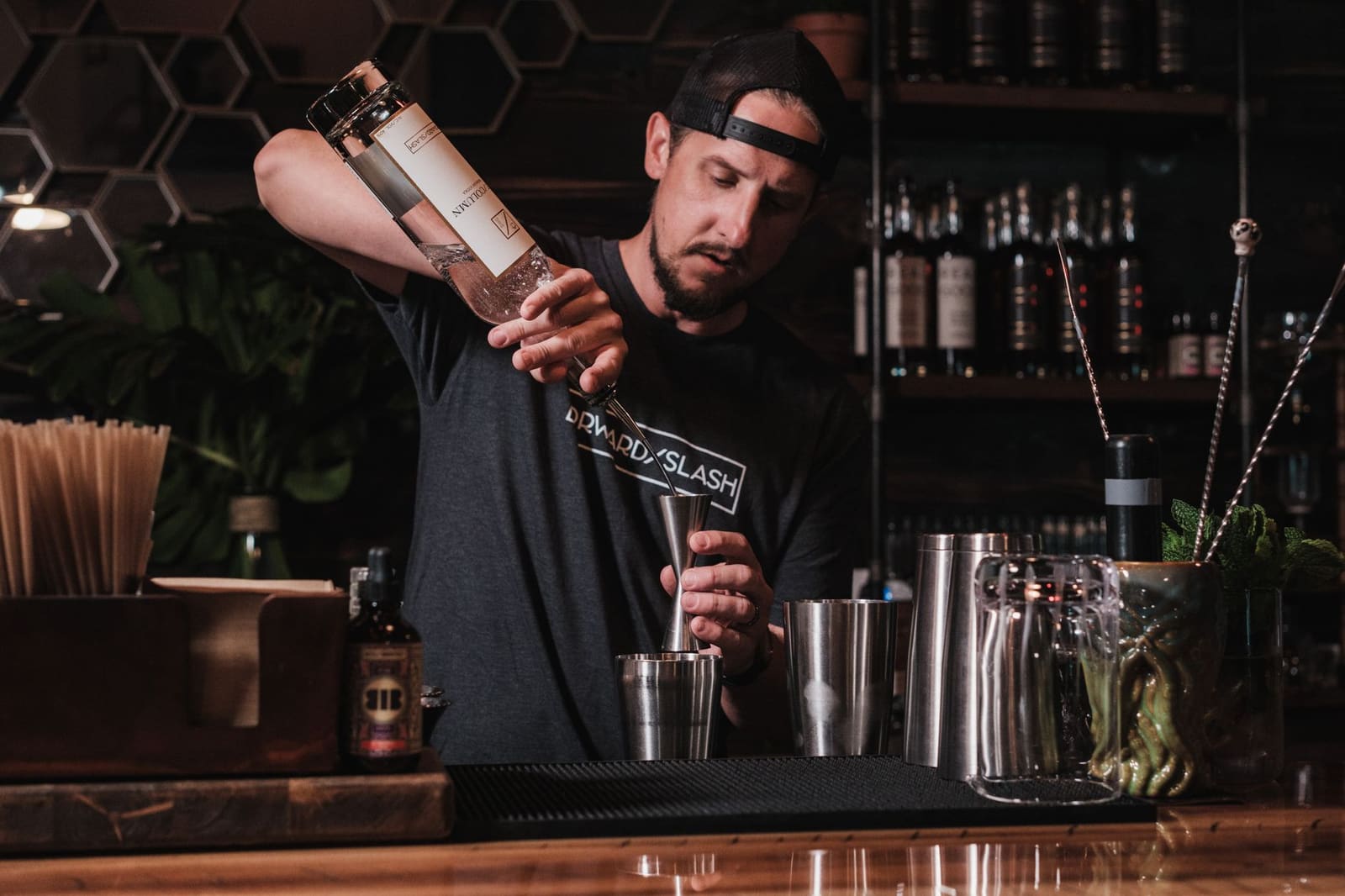 Bartender mengt ingrediënten voor een cocktail achter de bar