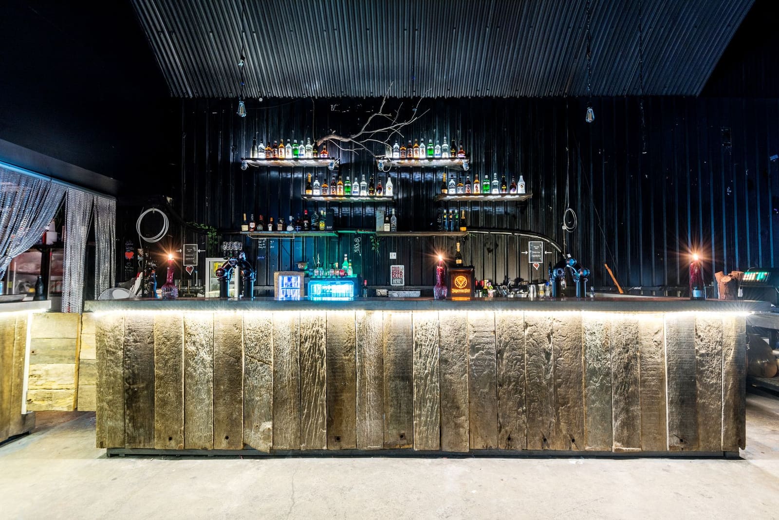 Een bar met achterverlichte flessen en glazen op de toog, klaar voor de avond.