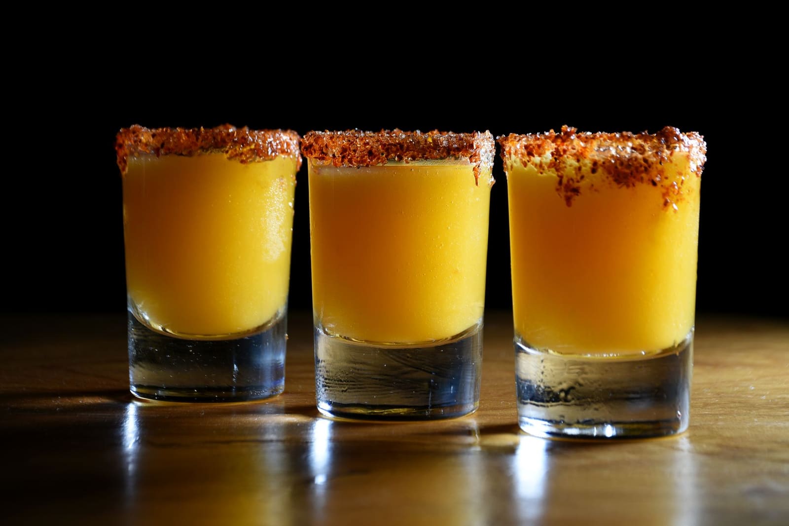 Tequila in een shotglas met zout en limoen op een houten tafel.