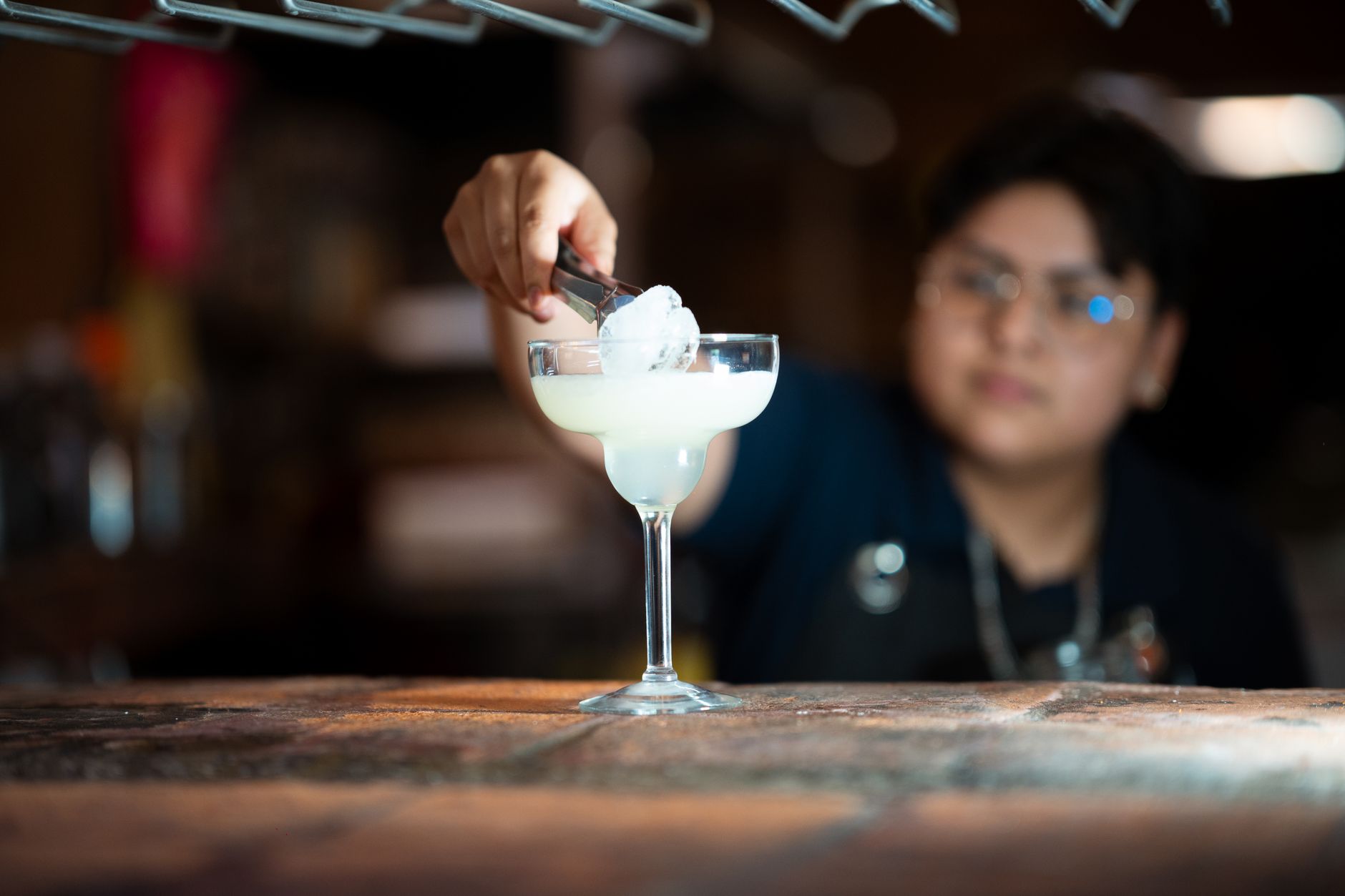 Bartender maakt een margarita met verse limoen en tequila achter de bar