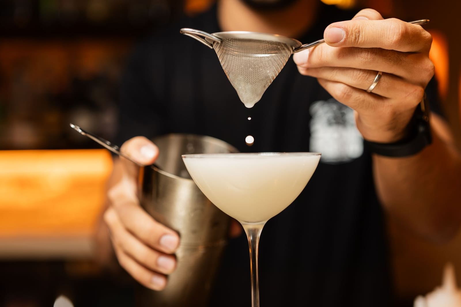 Bartender schenkt vodka in een glas achter de bar voor een cocktail